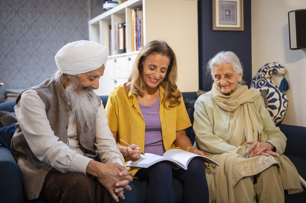 Three people sitting together reviewing documents in a comfortable supported living home.