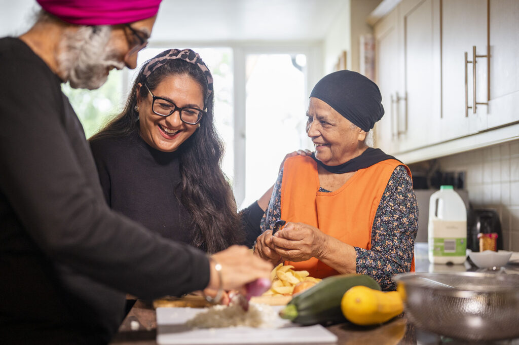 People preparing food together in a bright kitchen within a supported living home.