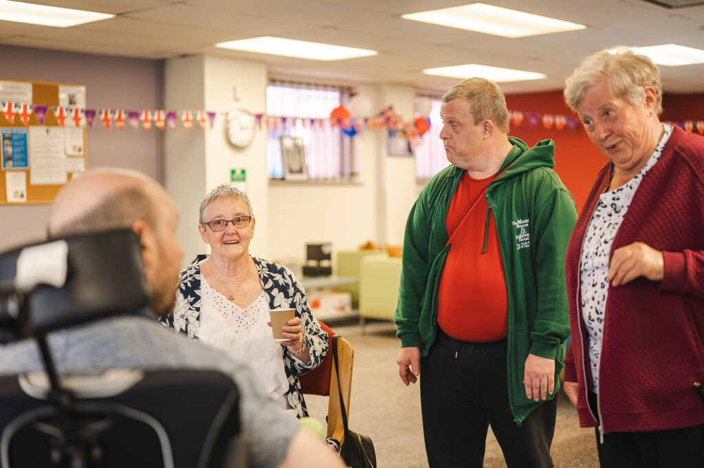 Group of people interacting in a communal area inside a supported living or care home setting.