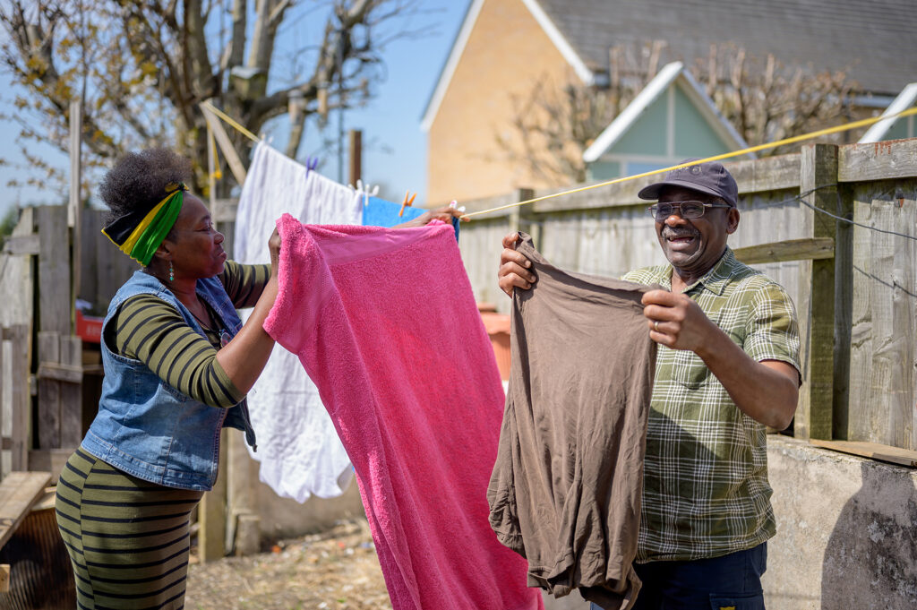 People hanging laundry together outdoors as part of community support services.