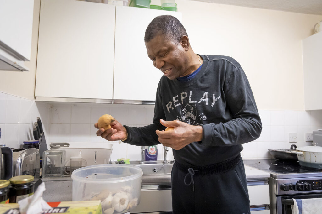 Person preparing food in a home kitchen as part of independent living support.